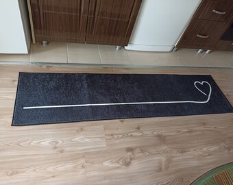May include: A black and white doormat with a white heart design. The heart is drawn with a single line.