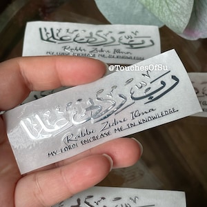 May include: A silver sticker with Arabic calligraphy and the text "Rabbe Zidne Ilma" which translates to "My Lord Increase Me In Knowledge".