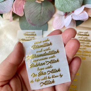 May include: A small, translucent sticker with gold lettering. The text reads "start with Bismillah, end with Alhamdulillah, appreciate with Subhan Allah, hope with In Sha Allah, & life will be bless by Allah."