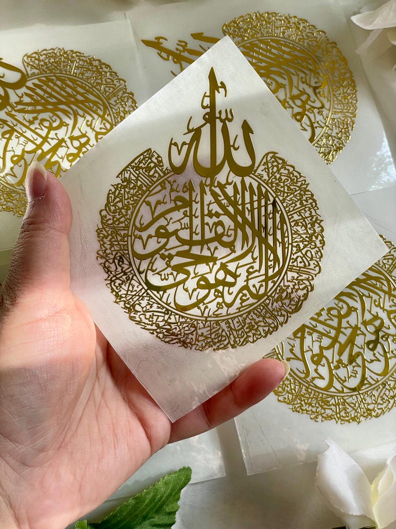 May include: Gold foil stickers with Arabic calligraphy. The stickers feature a circular design with the word "Allah" in the center. The stickers are on a white background.