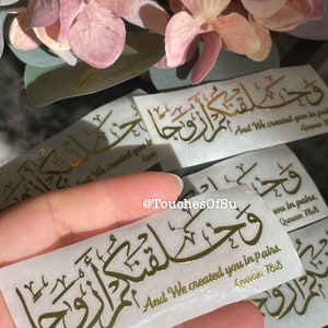 May include: Gold foil sticker with Arabic calligraphy and the text "And We created you in pairs. Quran 78:8".