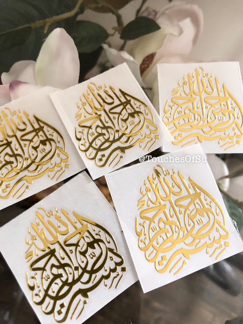 May include: Five gold foil stickers with Arabic calligraphy on a white background. The calligraphy says "Allah" in Arabic.