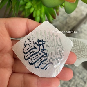 May include: Silver metallic sticker with Arabic calligraphy on a white background. The sticker is shaped like a diamond and has the text "@TouchesOfSu" in the top right corner.