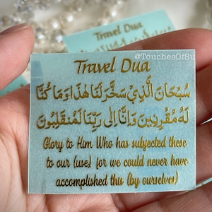 May include: A light blue card with gold lettering that reads "Travel Dua" and includes an Arabic prayer in gold lettering. The text below the prayer reads "Glory to Him Who has subjected these to our (use) for we could never have accomplished this (by ourselves)".