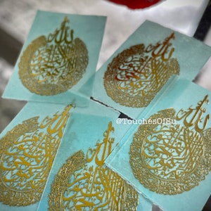 May include: Five gold-colored stickers with Arabic calligraphy on a light blue background. The stickers feature a circular design with intricate details. The text on the stickers reads "@TouchesOfSu".