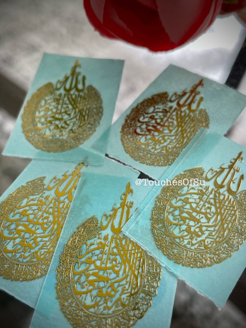 May include: Five gold-colored stickers with Arabic calligraphy on a light blue background. The stickers feature a circular design with intricate details. The text on the stickers reads "@TouchesOfSu".
