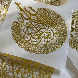 May include: Multiple gold-colored stickers with intricate Arabic calligraphy. The stickers feature a circular design with the word "Allah" in the center.