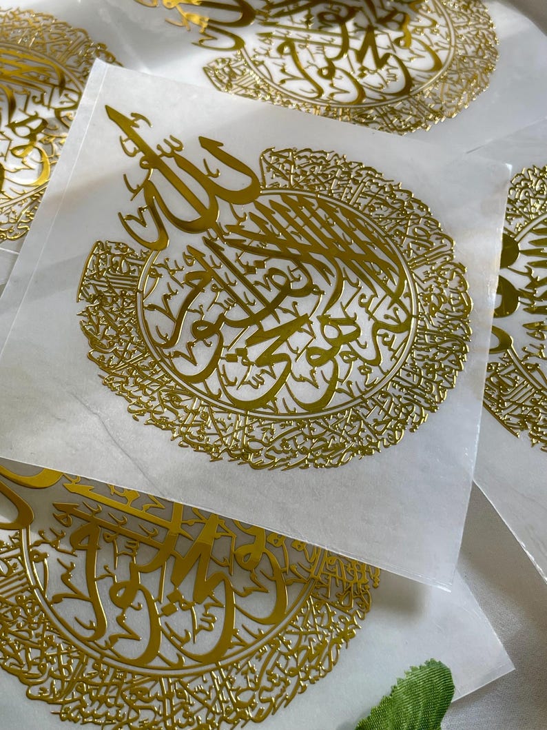 May include: Multiple gold-colored stickers with intricate Arabic calligraphy. The stickers feature a circular design with the word "Allah" in the center.