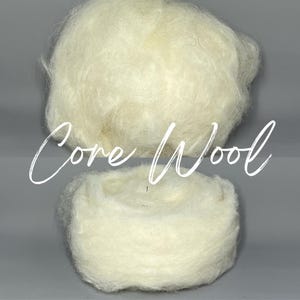May include: Two fluffy, off-white balls of core wool are displayed against a gray background. The text "Core Wool" is written in a cursive font across the image. The wool appears soft and ready for crafting projects.