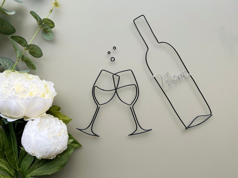Może przedstawiać: Szklana rzeźba z drutu przedstawiająca dwa kieliszki do wina, kt&oacute;re się toastują, z butelką wina, na kt&oacute;rej napisano "Wine".