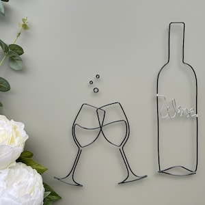 Może przedstawiać: Szkicowa rzeźba z drutu przedstawiająca dwa kieliszki do wina, kt&oacute;re się zderzają, oraz butelkę wina z napisem "wine".