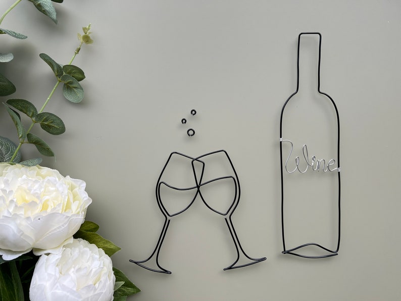 Może przedstawiać: Szkicowa rzeźba z drutu przedstawiająca dwa kieliszki do wina, kt&oacute;re się zderzają, oraz butelkę wina z napisem "wine".