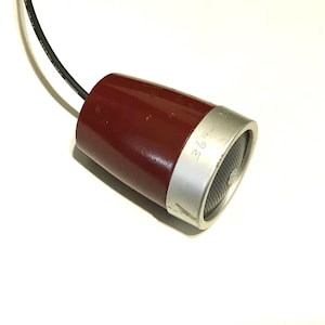 May include: A maroon, cone-shaped microphone with a silver-toned metal rim and a black mesh grille. A black electrical cord extends from the narrow end of the device. The silver rim features the etched text 364-85.