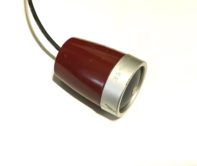 May include: A maroon, cone-shaped microphone with a silver-toned metal rim and a black mesh grille. A black electrical cord extends from the narrow end of the device. The silver rim features the etched text 364-85.