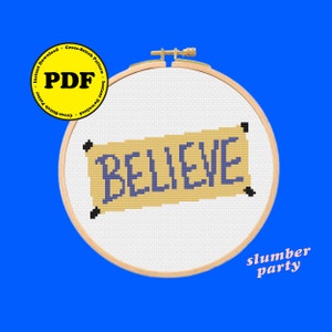 Peut inclure: Un motif de point de croix représentant une bannière avec le mot "BELIEVE" en lettres violettes sur un fond jaune. Le motif est présenté dans un cercle de broderie en bois. Le texte "slumber party" est écrit sous le cercle.