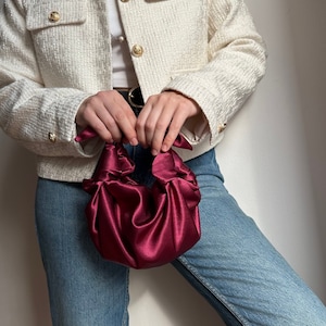 May include: A white tweed jacket with gold buttons and a burgundy satin handbag.