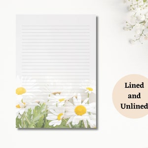 May include: White lined notepad with a daisy floral design at the bottom. The daisies have white petals and yellow centres. The text "Lined and Unlined" is in a beige circle.