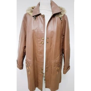 Könnte beinhalten: Eine braune Lederjacke mit einem Pelz gefütterten Kapuze. Die Jacke ist lang und hat dekorative Nähte an den vorderen Taschen.