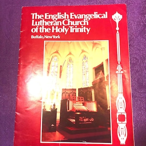 May include: A red pamphlet with the title "The English Evangelical Lutheran Church of the Holy Trinity, Buffalo, New York". The pamphlet features a photo of a church interior with a large pipe organ.