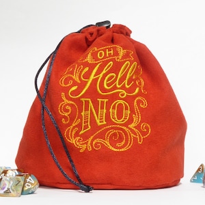 Könnte beinhalten: Ein roter Samt-Würfelbeutel mit einem goldenen Stickmuster, auf dem "Oh Hell No" steht. Der Beutel wird mit einem schwarzen Kordelzug geschlossen. Vor dem Beutel liegen mehrere schillernde Würfel.