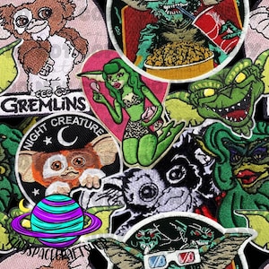 May include: A selection of embroidered patches showcasing characters and imagery from the film "Gremlins." The patches include various Gremlin designs, a pin-up style Gremlin, and the text "Gremlins" and "Night Creature."