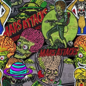 Op de afbeelding: Een verzameling geborduurde patches met personages en afbeeldingen uit de film "Mars Attacks". De patches tonen groenhuidige aliens, vliegende schotels en de titel van de film in rode letters. De patches zijn in verschillende vormen en maten.
