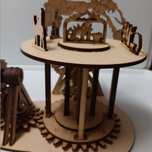 May include: A wooden Christmas carousel with a nativity scene, a camel, and a star. The carousel is made of wood and has a brown stain. The carousel is on a wooden base.