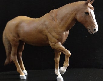 May include: A brown horse figurine with white hooves, standing on a black surface.