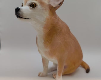 May include: A detailed figurine of a Chihuahua dog in a seated position. The dog has a light brown and white coat, with large, upright ears and a focused gaze. The figurine is set against a plain white background.