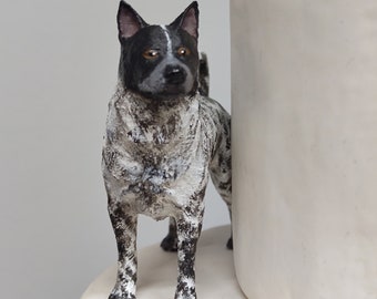 May include: A black and white dog figurine with brown eyes, standing on a white cake.