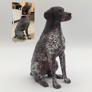 May include: A brown and white German Shorthaired Pointer dog figurine. The figurine is sitting with its head turned to the side and its ears perked up.