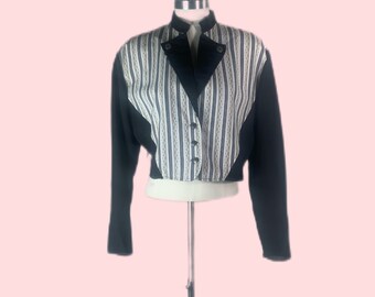 May include: A vintage cropped jacket with a striking design. The jacket features black sleeves and a black collar, with a patterned front panel of vertical stripes in cream, navy, and light blue. It has three buttons and is displayed on a mannequin.