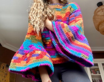 May include: A colorful crocheted sweater with bell sleeves. The sweater is made with a variety of bright colors, including red, orange, yellow, green, blue, and purple.