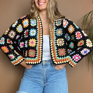May include: A colorful crochet cardigan with a black background and a variety of colored squares. The cardigan is cropped and has a loose fit.