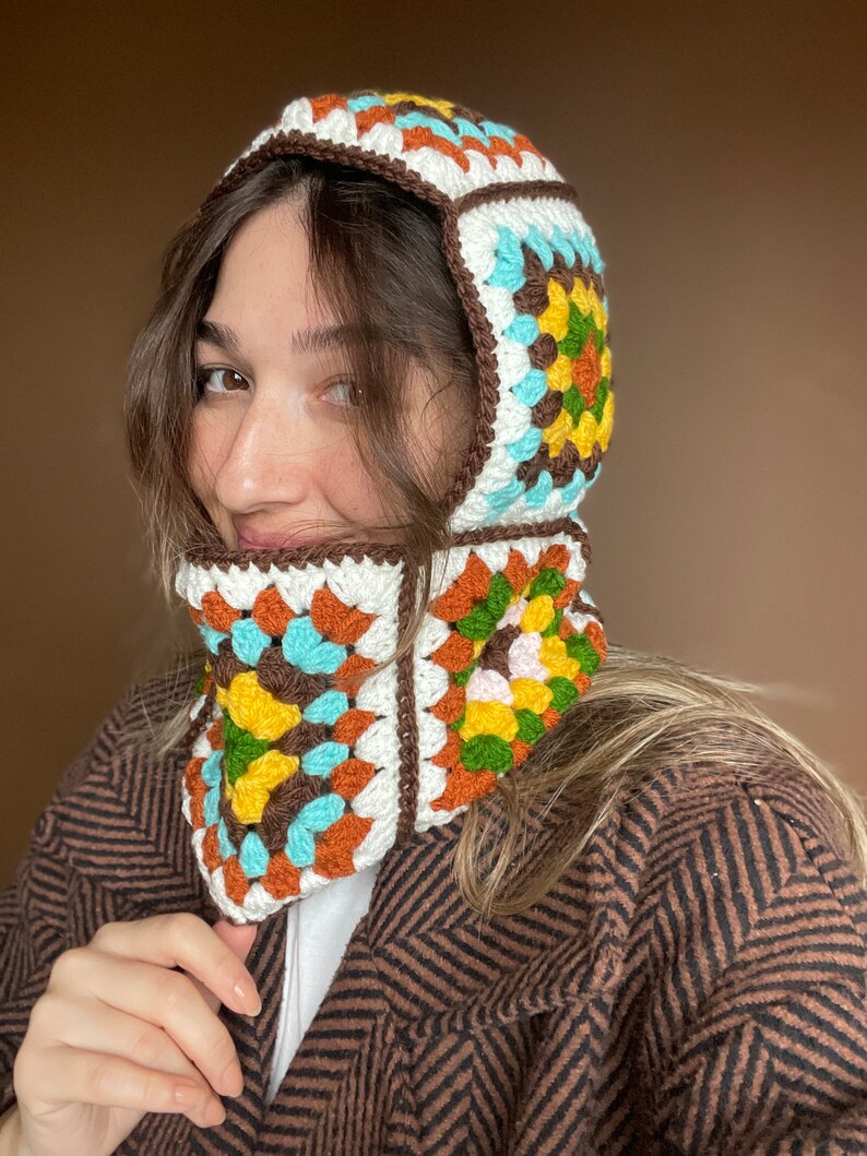 May include: A brown, white, blue, orange, and green crocheted hooded scarf with a geometric pattern.