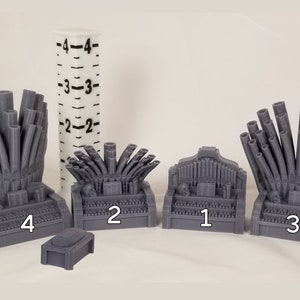 May include: Five gray 3D printed miniature pipe organs, numbered 1 through 4, with the largest organ measuring approximately 4 inches tall. The organs are arranged in a row on a white surface.