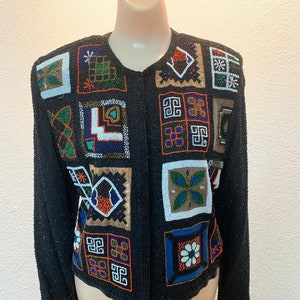 Könnte beinhalten: Eine schwarze Perlenjacke mit einem geometrischen Muster in verschiedenen Farben, darunter Orange, Blau, Grün und Weiß.