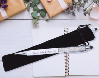 May include: A white pen with a crystal-like design and a black velvet pouch. The pen is engraved with the text "Francis - Justin ♥ July 30 2021".