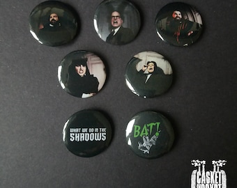 May include: Set of seven black and white button pins featuring images from the classic horror film "What We Do in the Shadows". The pins feature characters from the film, including the vampire roommates, and the text "What We Do in the Shadows" and "Bat!"