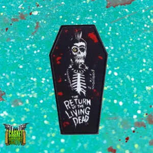 Puede incluir: Parche bordado en blanco y negro de un esqueleto en un ataúd con el texto "The Return of the Living Dead".