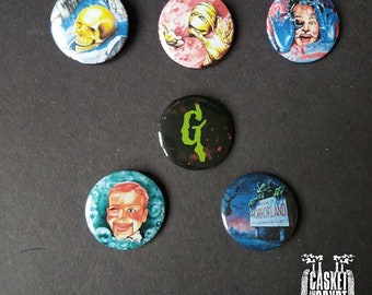 May include: Six round, colourful, pinback buttons with horror movie themes. The buttons feature images of a skull, a mummy, a man with a blue face, a green letter G, a man with a clown face, and a monster holding a sign that says "Horrorland".