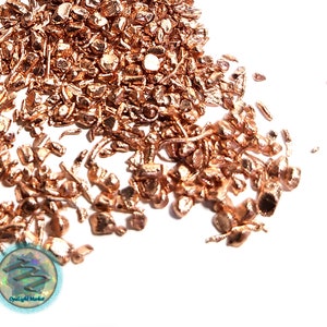 May include: A pile of copper shavings, small pieces of copper metal, on a white background.