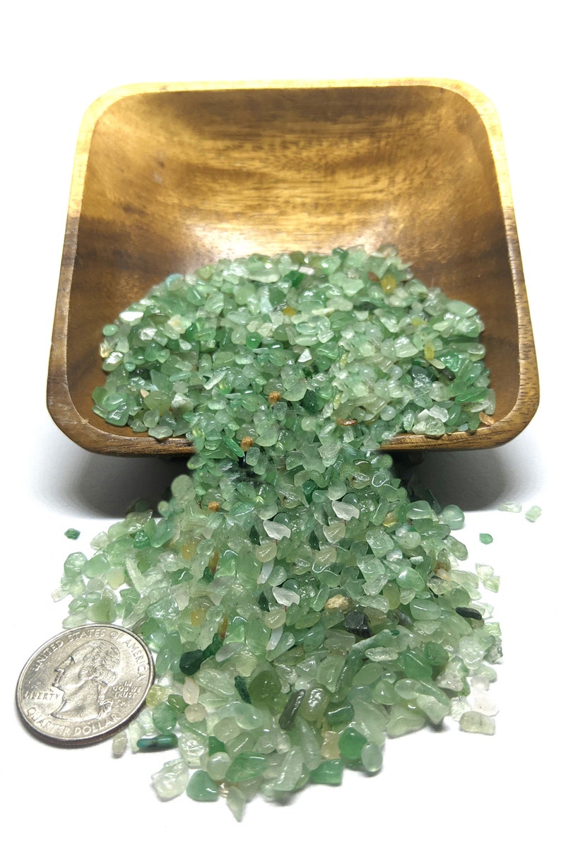 Puede incluir: Un cuenco de madera lleno de peque&ntilde;as piedras de aventurina verde pulidas. Una moneda est&aacute; al lado de las piedras para comparar el tama&ntilde;o. Las piedras son una mezcla de verde claro y oscuro, con algunas piezas transl&uacute;cidas.