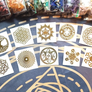 May include: Ten gold temporary tattoos featuring a variety of geometric and spiritual designs, including a tree of life, a flower of life, and a lotus flower.