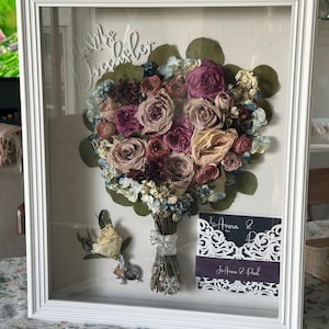 Shadow box with preserved wedding flowers. Also included are invites, cake topper, boutonniere.