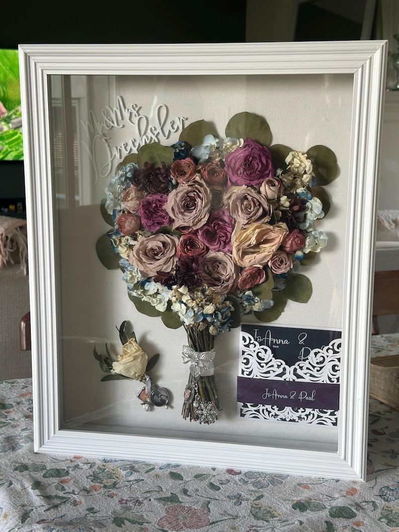 Shadow box with preserved wedding flowers. Also included are invites, cake topper, boutonniere.