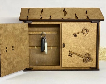 May include: Wooden key holder shaped like a house with a hinged door. The key holder has hooks inside for hanging keys and decorative key cutouts on the front.