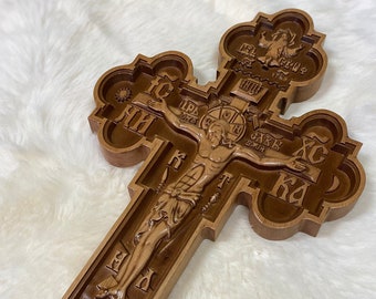 May include: A wooden cross with intricate carvings, featuring a depiction of Jesus Christ on the cross. The cross is decorated with Cyrillic lettering and a skull and crossbones at the base.