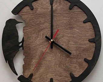 May include: A wooden clock with a black silhouette of a bird on a tree trunk. The clock face is brown with black hour markers and black hands.