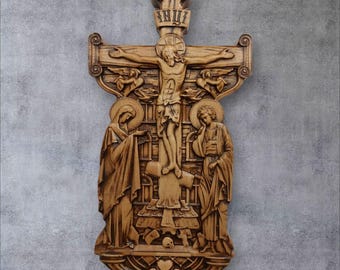 Puede incluir: Un crucifijo de madera tallada con Jesucristo en la cruz, flanqueado por la Virgen María y San Juan. La cruz está decorada con tallas intrincadas y las figuras están representadas de forma realista.